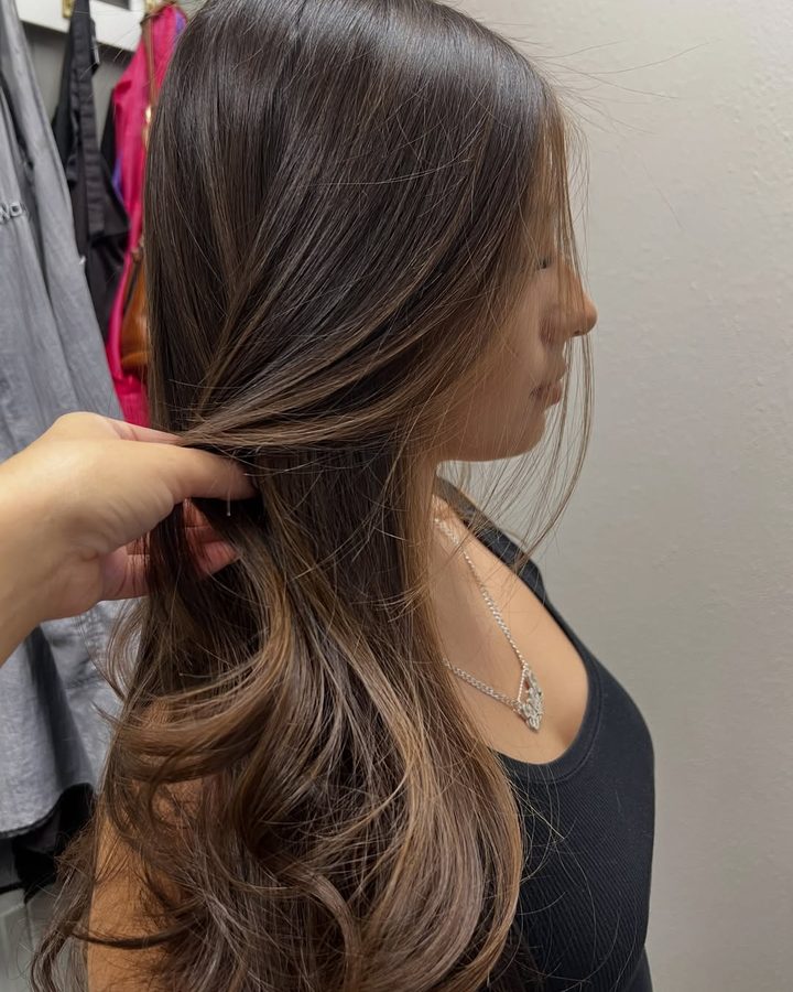 Long brunette hair with soft caramel balayage, styled in loose waves